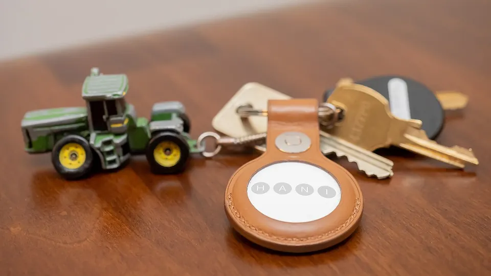 An Apple AirTag, a small white disc tracker, next to its packaging