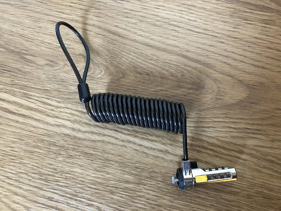 A coiled steel laptop cable lock with its lock head and keys